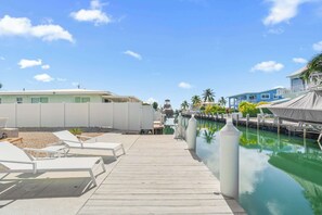 A wooden pier leading to a pool area with lounge chairs and a water feature. - The Salty Coconut ~ Waterfront ~ Dock ~ Hot Tub (Marathon)