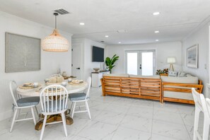 A spacious living area with a dining table, chairs, a sofa, and a wooden bench. - Paradise Vacation Home (St. Augustine)
