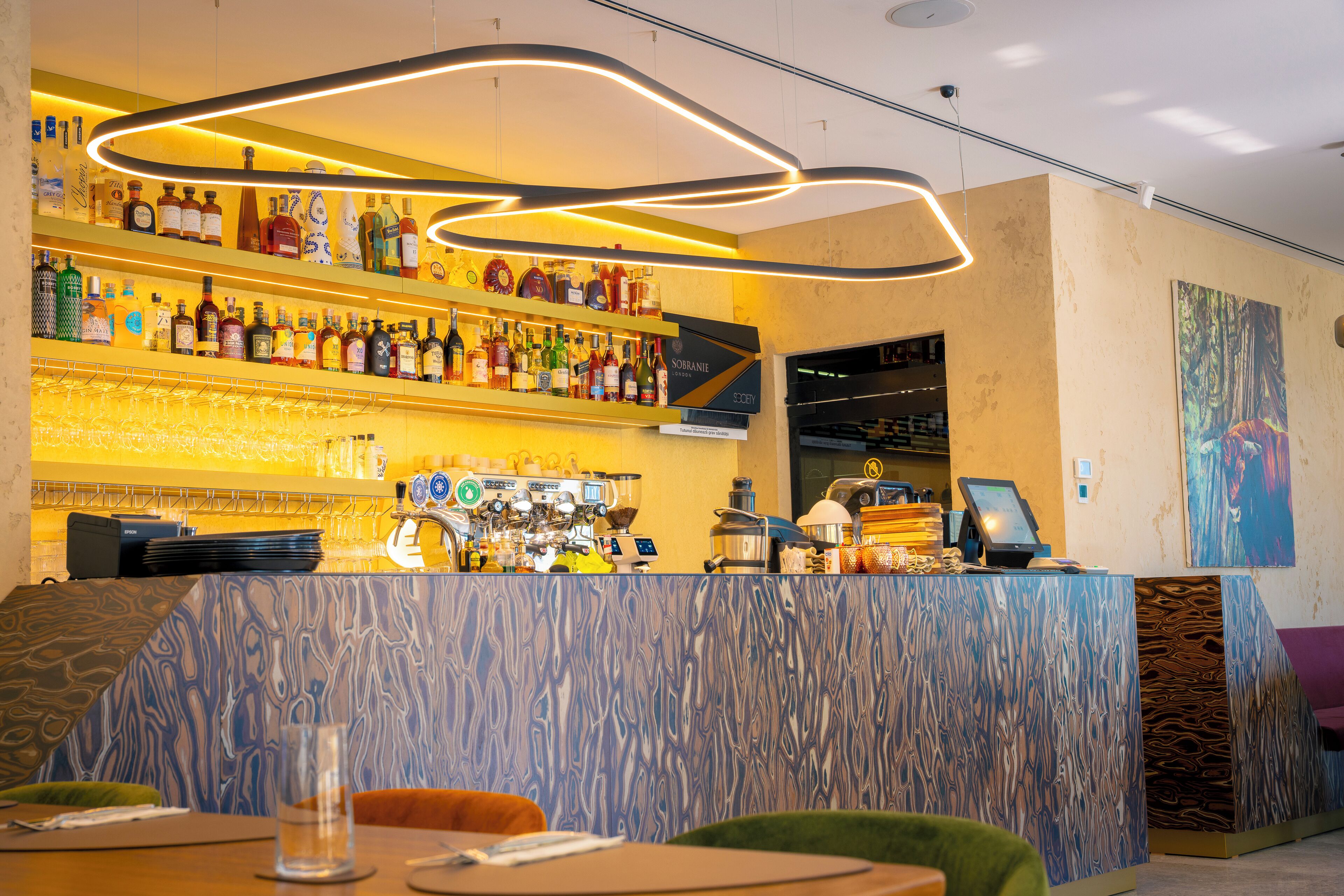 A bar area with shelves of liquor bottles, a coffee machine, and a counter with a payment terminal.