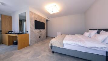 Un dormitorio moderno con cama, escritorio y televisor en la pared.