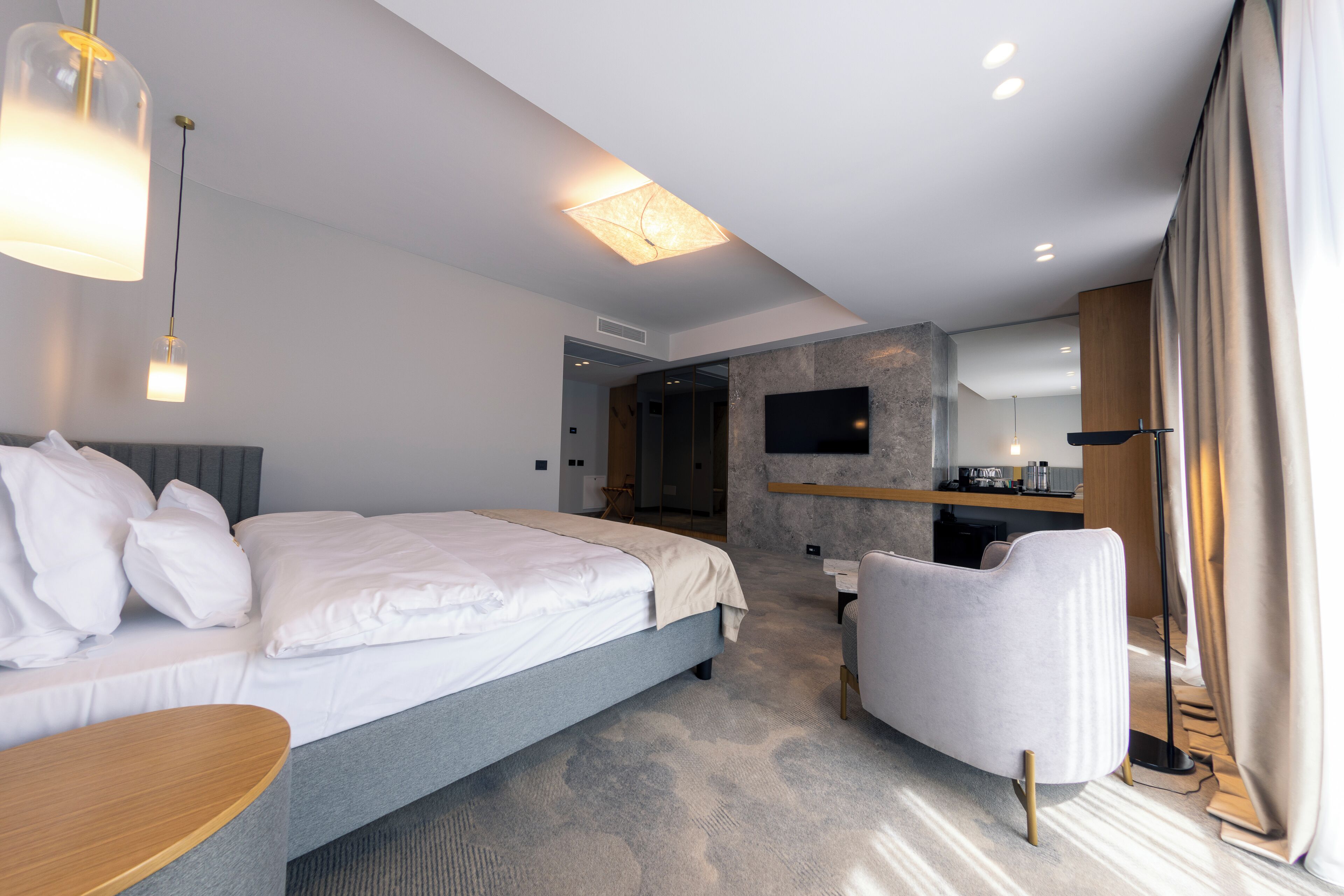Een moderne hotelkamer met een groot bed, een bureau, een stoel, een televisie en een badkamer op de achtergrond.