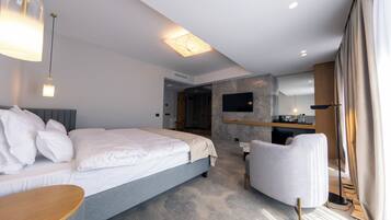 Een moderne hotelkamer met een groot bed, een bureau, een stoel, een televisie en een badkamer op de achtergrond.