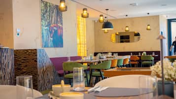 A restaurant with a modern interior, featuring a mix of seating arrangements and a large painting on the wall.