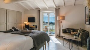 Een slaapkamer met een bed, een bureau met lamp, een bank en uitzicht op het groen.