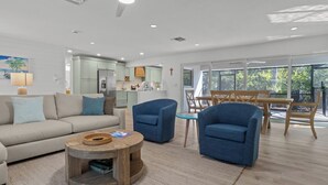 Una sala moderna con un sofá, dos sillones, una mesa de centro y un comedor con mesa y sillas.