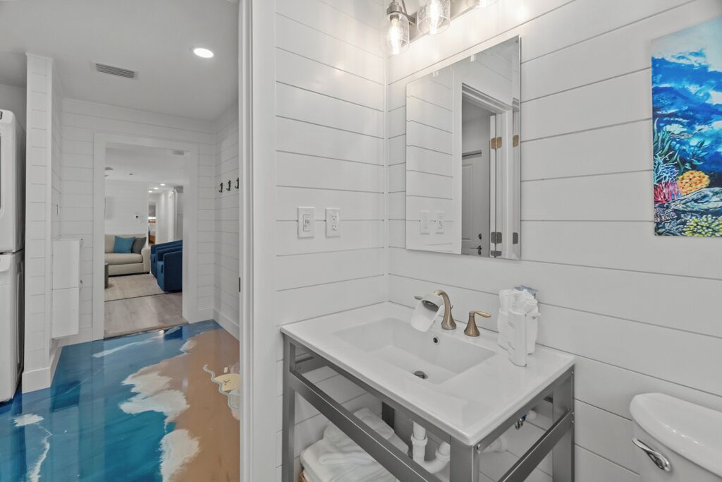 Une salle de bain moderne avec un lavabo blanc, un miroir et des toilettes.