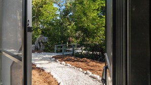 Un sendero que atraviesa un jardín con un puente de madera y un muro de piedra.