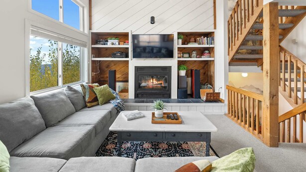 Una sala de estar moderna con chimenea, un sofá, una mesa de centro y una escalera.