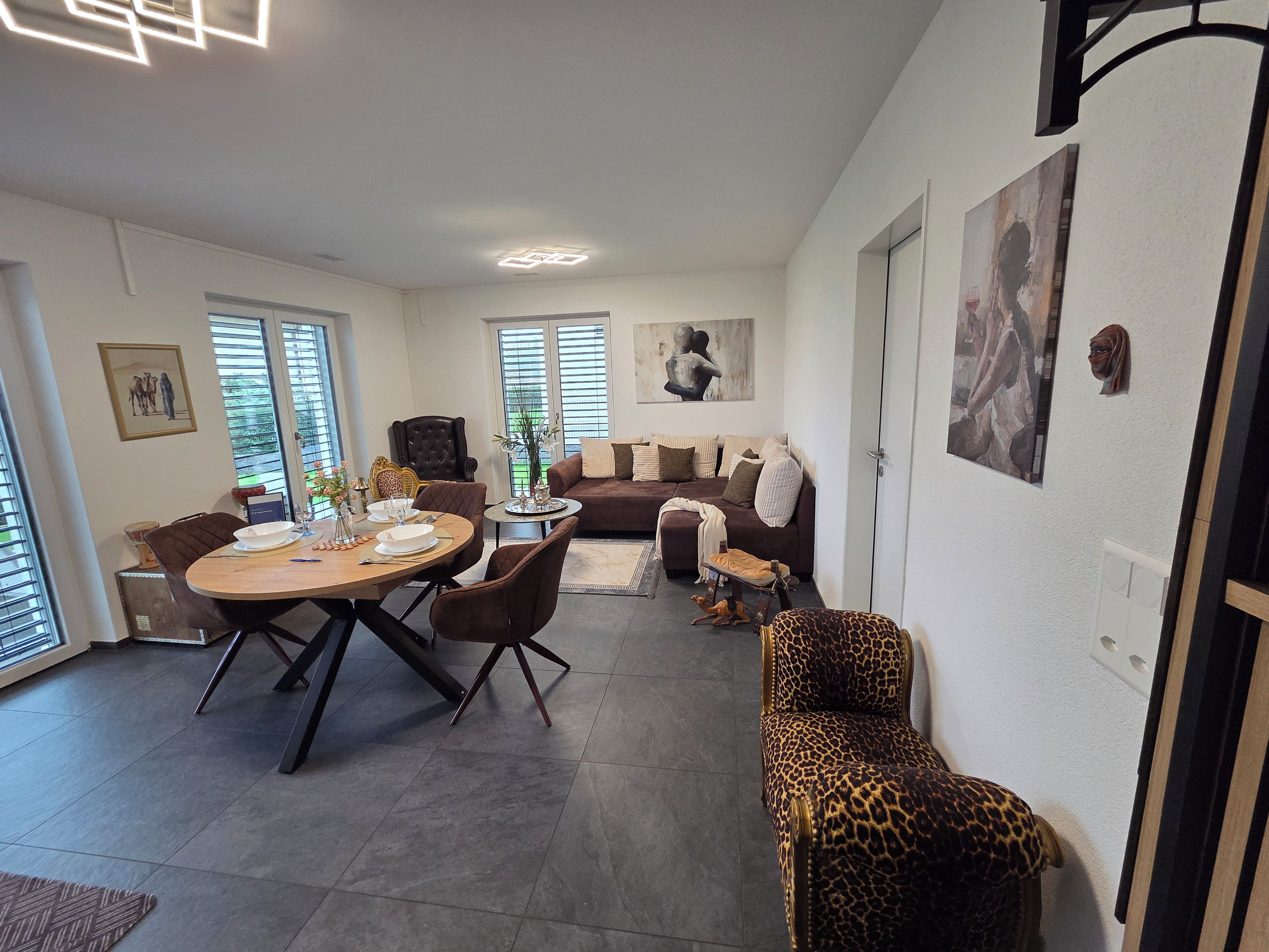 A modern living room with a dining area, a sofa set, and a leopard-print chair.