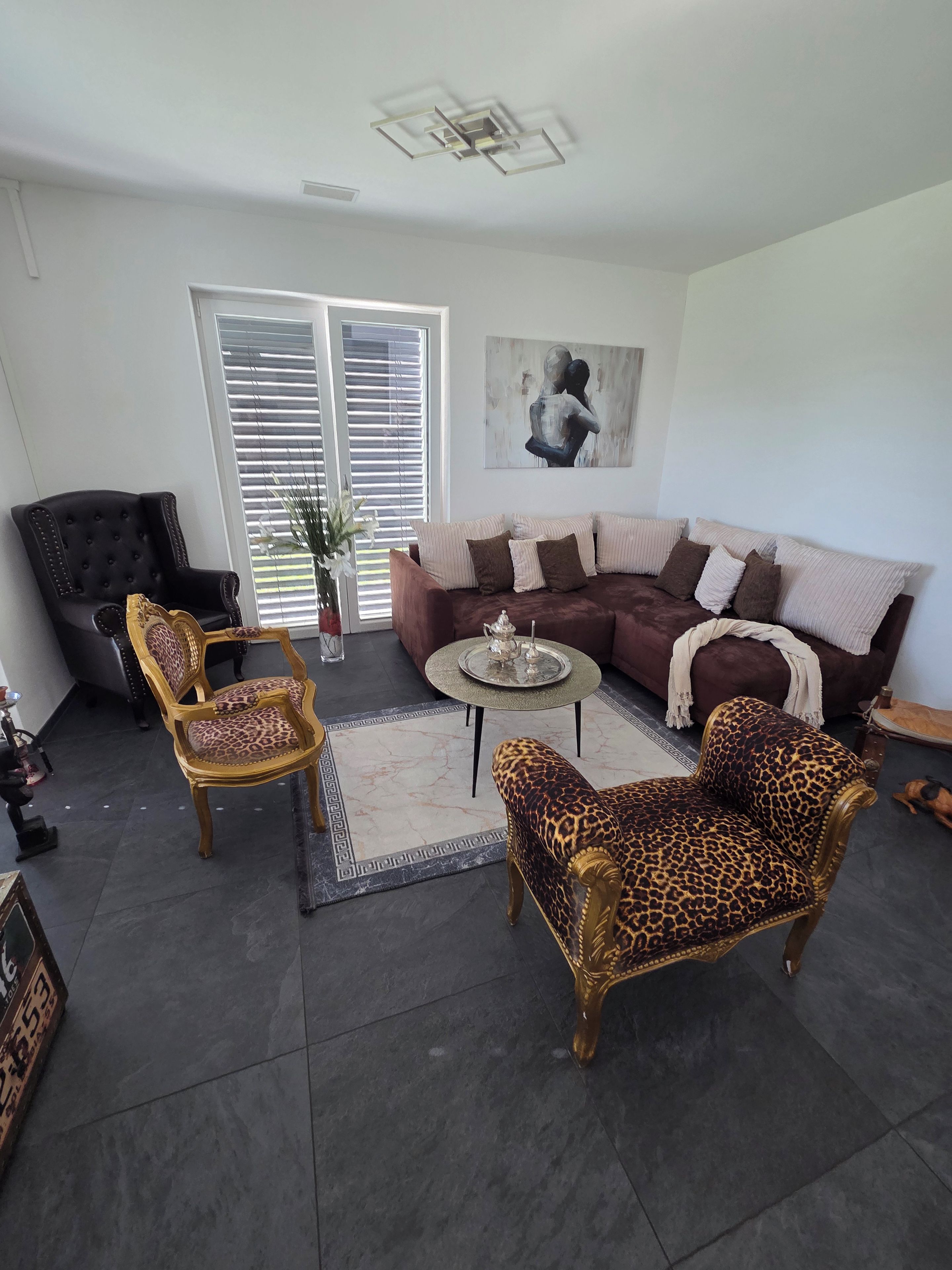 A living room with a sectional sofa, two armchairs, a coffee table, and a black leather armchair.