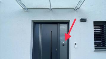 Un edificio moderno con una porta d'ingresso scura, un ingresso in vetro e una piccola finestra con persiane.