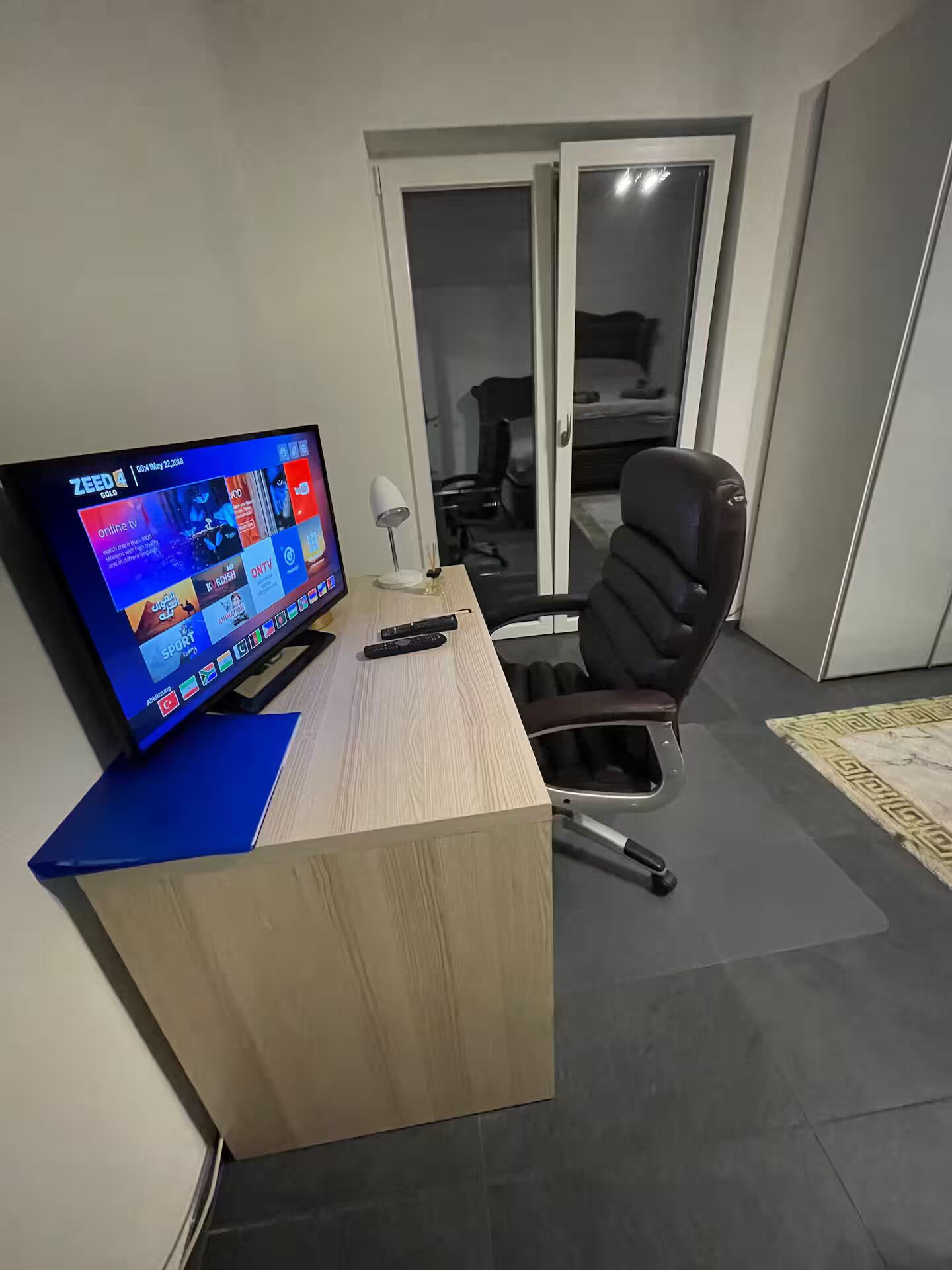 Un espace de bureau moderne comprenant un bureau, une chaise et un téléviseur affichant l’interface d’un service de diffusion en continu.
