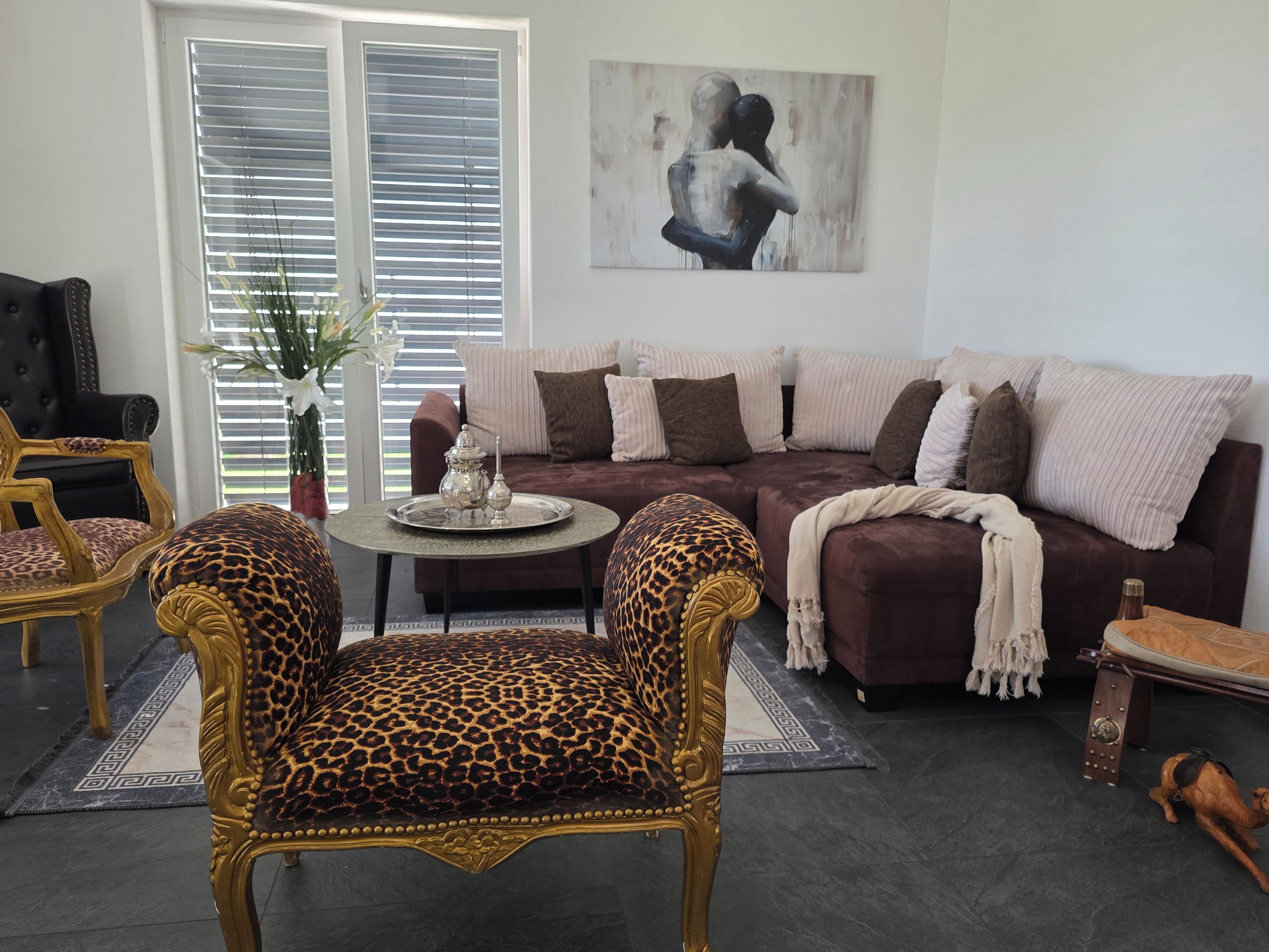 A living room with a sofa, two armchairs, a coffee table, and a painting on the wall.