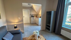 Una sala de estar moderna con un sofá, una mesa de centro y una cocina al fondo.