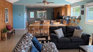 A spacious living area with a sofa, a dining table, and a kitchen in the background.
