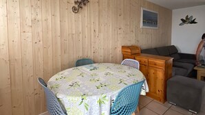 Un comedor con una mesa redonda cubierta con un mantel floral, rodeado de sillas azules.