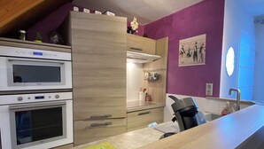 Una cocina moderna con dos hornos, una encimera de madera y una pared de acento púrpura.