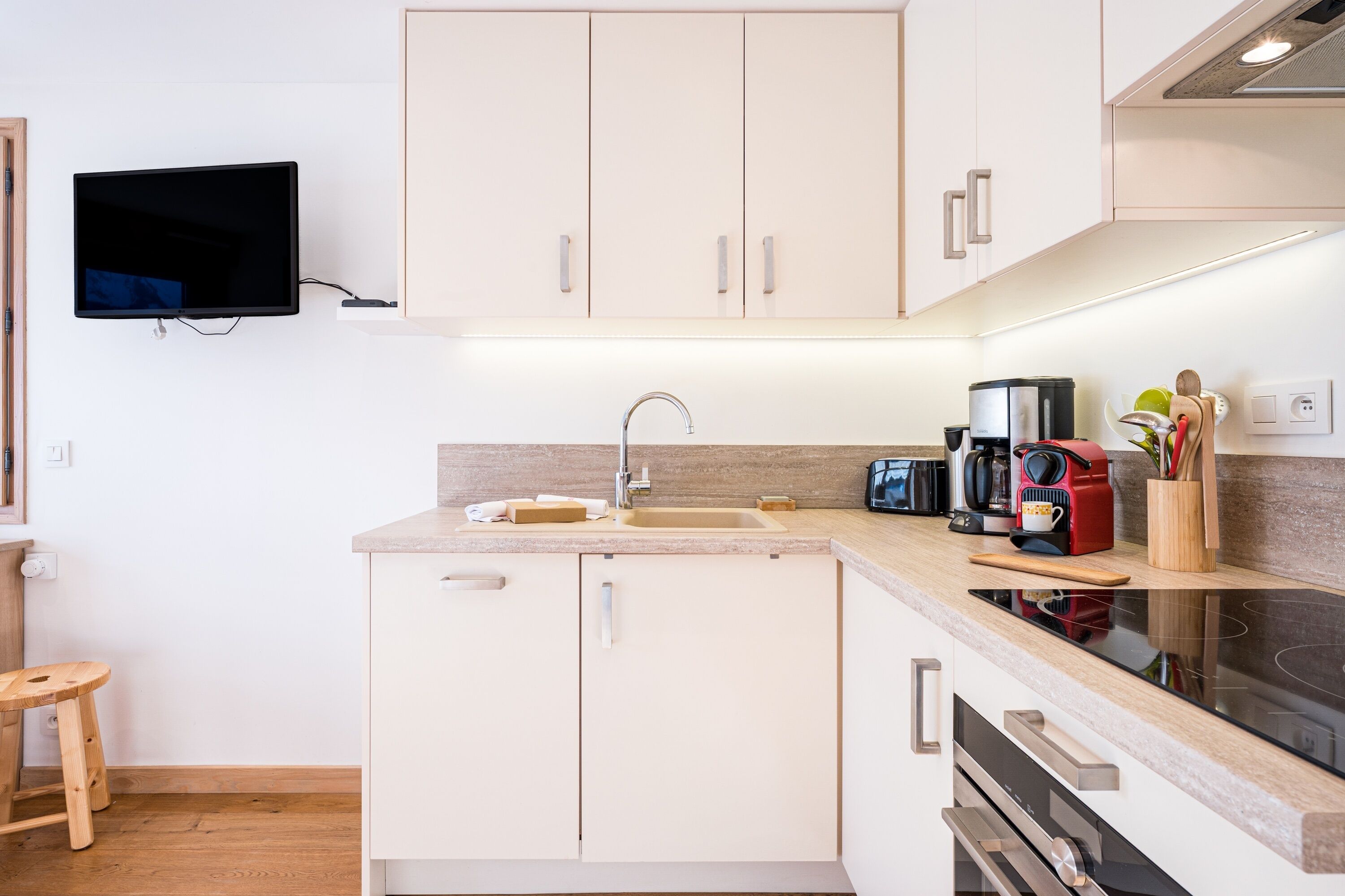 Una cucina moderna con mobili bianchi, forno integrato, microonde e macchina del caffè.