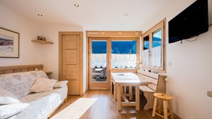 A cozy room with a bed, a dining table, and a TV. - Le Beauregard 1 - Vue Montagne (Le Grand Bornand)