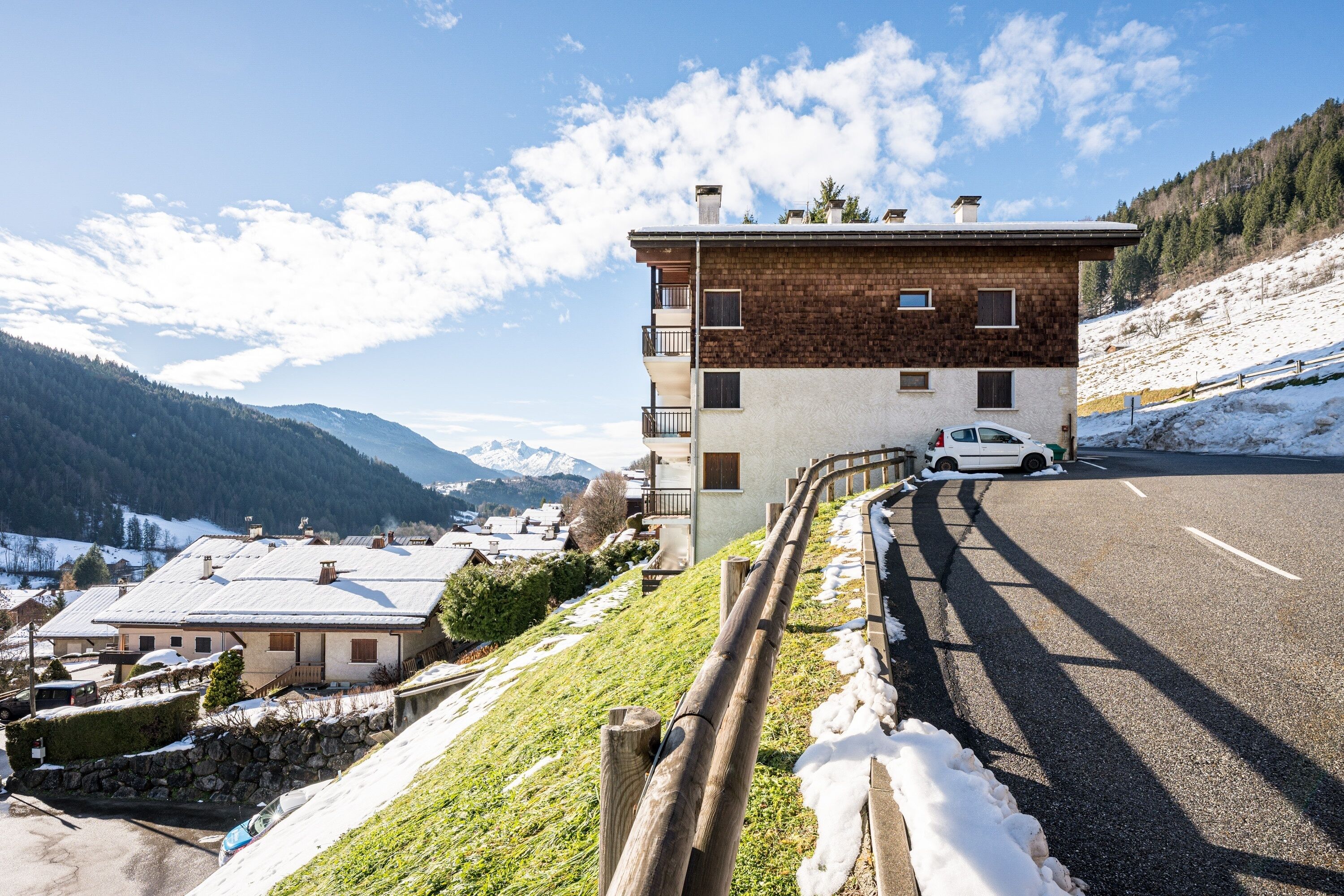 A two-story building with a sloped roof, located beside a road with snow on the ground.