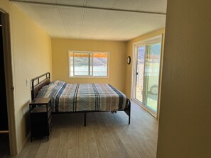 Une chambre à coucher comprenant un lit, une table de chevet, une fenêtre donnant sur une montagne et une porte-fenêtre coulissante qui mène à un patio.