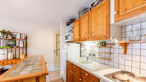Una cocina con armarios de madera, un refrigerador blanco, un microondas y un lavabo.