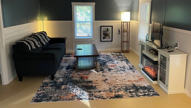 A living room with a sofa, coffee table, rug, fireplace, and a framed picture on the wall. - The Jumping Mullet in charming Crystal River, walk to bars, restaurants & bay (Crystal River)
