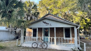A small wooden cabin with a porch, a bicycle parked in front, and a bird mural on the front wall. - The Jumping Mullet in charming Crystal River, walk to bars, restaurants & bay (Crystal River)