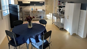 A modern kitchen with white cabinets, a black refrigerator, and a dining area with a round table and chairs. - The Jumping Mullet in charming Crystal River, walk to bars, restaurants & bay (Crystal River)