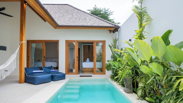 A modern poolside area with a pool, blue lounge chairs, and a variety of tropical plants. - Stylish 2BR Private Pool Villa • 5 Mins to Bingin Beach (Bali)
