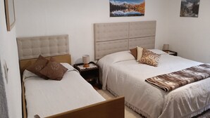 Ein Schlafzimmer mit zwei Betten, jeweils mit Kopfteil und Kissen. Es gibt zwei Nachttische mit Lampen und einen kleinen Tisch mit einer Kerze.