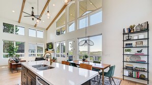 Una cocina amplia con una isla grande, vigas de madera en el techo y grandes ventanales con vistas al exterior.