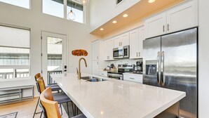 Una cocina moderna con armarios blancos, electrodomésticos de acero inoxidable y una isla grande con taburetes de bar.