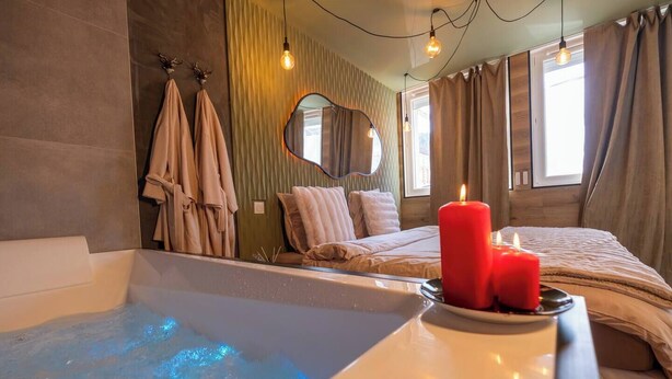 A modern bathroom with a bathtub, a mirror, and a red candle on the side. - L'Écrin des Alpes - Romantic Suite with Jacuzzi - Centre Saint-Étienne (Saint-Étienne)