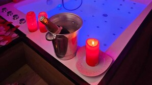 A spa bath with a metal bucket, candles, and a handheld showerhead. - L'Écrin des Alpes - Romantic Suite with Jacuzzi - Centre Saint-Étienne (Saint-Étienne)