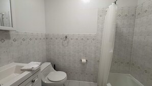 Un baño con inodoro, lavamanos y ducha.