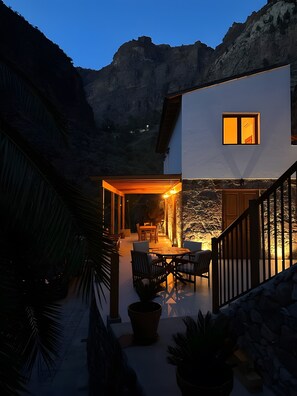 Una casa moderna con patio, area salotto esterna e montagne sullo sfondo.