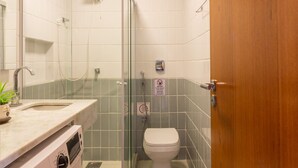 Une salle de bain compacte avec une douche à parois de verre, des toilettes et un lave-linge.