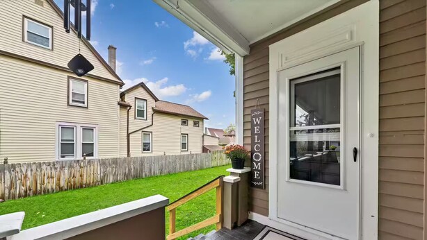 A residential porch with a welcome sign, a wooden bench, and a small planter with flowers. - Western-Themed & Conveniently-Located Apartment in Tonawanda (Tonawanda)
