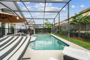 Ein Schwimmbad mit Glasveranda, einer Hängematte und einem Sonnenschirm.