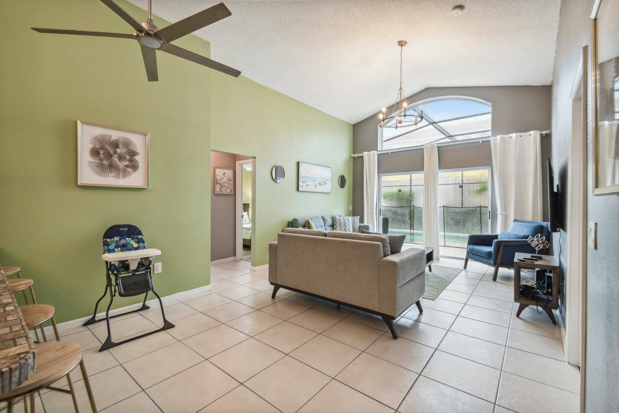 A spacious living room with a high ceiling fan, a large window, and a view of the outdoors.