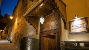 Une rue étroite, bordée d’un immeuble dont la façade est ornée d’une porte en bois et de décorations murales élaborées.