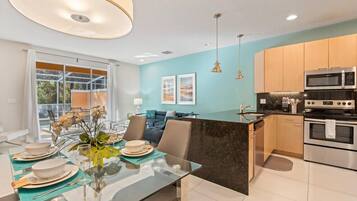 A modern kitchen with a central island, stainless steel appliances, and a dining area with a glass table and chairs.