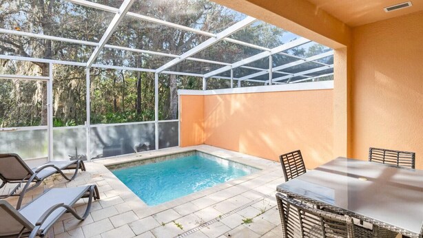 A covered outdoor swimming pool with a glass ceiling, surrounded by lounge chairs and a dining table. - Amazing Family House w pvt Pool - 1605 (Almont)