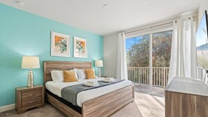 A bedroom with a bed, two bedside tables, a nightstand, a large window with a view of trees, and two wall-mounted artworks. - Amazing Family House w pvt Pool - 1605 (Almont)