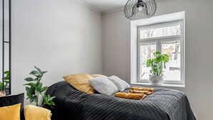 Ein Schlafzimmer mit Bett, Fenster und einer Pflanze.