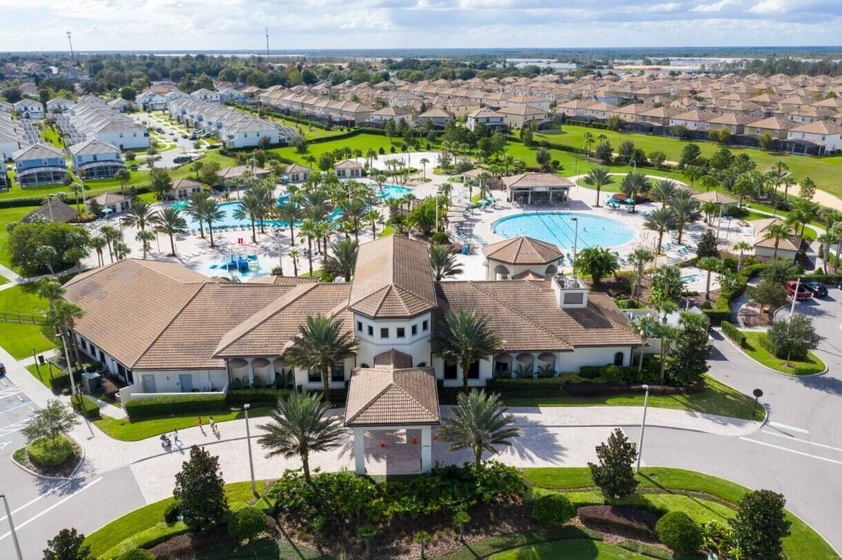 A residential area with a large house featuring a swimming pool, a gazebo, and a tennis court.
