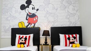 Une chambre d’hôtel avec deux lits, chacun agrémenté d’oreillers à l’effigie de Mickey Mouse et d’une fresque murale représentant Mickey Mouse.