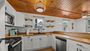 A modern kitchen with white cabinets, wooden countertops, a built-in stove, and a dishwasher. - Easy Walk to Beach & Nags Head Shops, Restaurants (Nags Head)