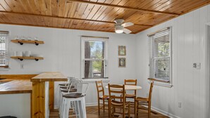 A dining area with a wooden ceiling, white walls, and a round table with chairs. - Easy Walk to Beach & Nags Head Shops, Restaurants (Nags Head)